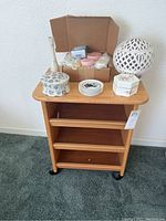 Front view of wooden rolling cart with items on top shelf