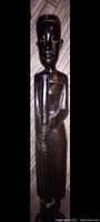 Full view of dark black ebony wood standing figure holding staff