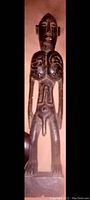 Front view photo of a dark wood tribal African male statue with detailed carvings and tattoos on the torso