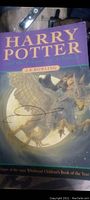 Photo of purple softcover book 'Harry Potter and the Philosopher's Stone' showing cover art of dragon and moon with author's autograph on front cover.