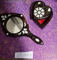 Top view of the hand mirror and heart-shaped jewelry box on a patterned background showing mother-of-pearl inlays and velvet interior