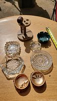 All ashtrays, the wooden pipe, and the wooden pipe holder on a wooden table under sunlight with a tape measure