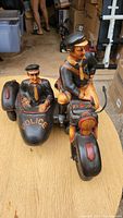 Side view of resin police motorcycle with sidecar and two officer figurines, showing details of the motorcycle seat, sidecar, and figures