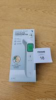 Front of box showing Sharper Image Touchless Thermometer with image of the device and LCD screen reading 98.6.
