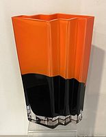 Front view showing zig zag edge design with bright orange upper section and black lower section blending smoothly transitioning into a thick clear glass base.
