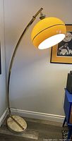 Full view of lamp in corner, fully extended arc body and marble base visible
