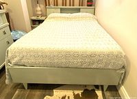 Bed front view showing footboard and bedding on metal frame