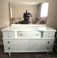 Front view of vintage white painted wooden dresser with mirror and visible drawer handles