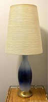 Front view of lamp showing full porcelain body, brass base and fiberglass shade.