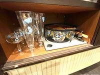 Close-up showing glasses and decorative tray inside the bar compartment shelf.