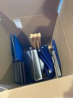 Top view photo showing assortment of binders, plaques, and embroidery hoop stand in a cardboard box.