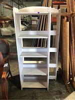 Front view of one white wooden bookcase showing five shelves and arched top.