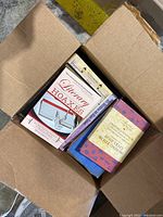 Top-down view inside an open box showing books including 'Literary Hoaxes' and 'A Short Guide to Ethics'.
