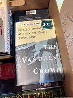 Books in an open box, showing 'The Vandals' Crown' by Gregory J. Millman with a 20% off sticker on cover.