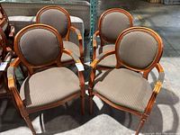 Four matching chairs with wooden frames and striped upholstered seats and backs. Chairs have oval backs and carved armrests. Visible scratches and fading on wood.