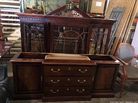 Front view of dark wood Thomasville china cabinet showing three glass doors with decorative lattice on top, and side cabinets.