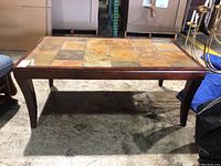 Front and side view of the stone tile top coffee table showing the top surface pattern, wooden frame and curved legs.
