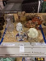 Lot of glassware, ceramic and copper teapots, decorative plates and figurines arranged on a table