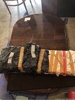 Photo of dining table top with two extension leaves wrapped in black and brown tape covering.