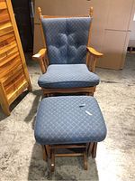 Front-facing view of wood frame glider chair with blue patterned removable cushions and matching ottoman