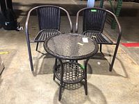 Two brown wicker chairs and round glass-top table shown from front, displaying whole set and dimensions.