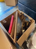 Several framed artworks and a mirror in a box, showing different frame styles and sizes.