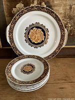 Seven Limoges plates arranged showing Bacchus center design and ornate border detail.