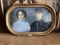 Full view of the oval framed antique portrait in bowed glass showing a man and woman.