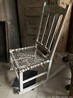 Side angle showing the rocking curved base, painted frame with wear, and sinew seat.
