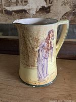 Photo of the front of the Royal Doulton pitcher showing detailed woman in purple gown and floral background