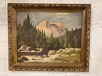 Front view of the framed oil painting showing the mountain landscape with trees, river, and rocks.