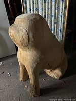 Front and side views of a large unfinished wood carving of an animal figure with prominent rounded ears or side features. Standing on four legs in rough form about over 2 feet tall.