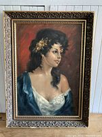 Full view of vintage framed portrait painting showing young woman with dark hair, yellow flowers, blue and white clothing.