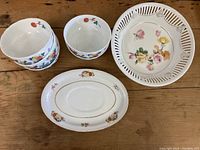 Top overview photo showing 3 small floral bowls stacked, oval dish and large pierced basket dish