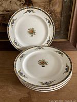 Eight vintage Johnson Bros. Pareek Marjorie plates stacked and displayed with central and rim floral and fruit designs.