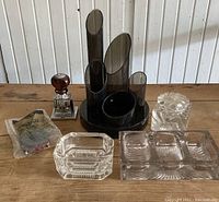 Top view showing the rotary date stamp with wood knob, black plastic desk organizer with multiple compartments, two glass inkwells, glass trinket dish with three compartments, and pack of rubber bands.