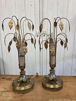 Pair of vintage metal table lamps shown front view. Both have a round base with intricate metalwork and multiple curved metal stems ending in metal leaves.