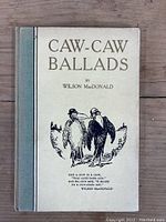 Front cover of vintage book titled 'Caw-Caw Ballads' by Wilson MacDonald, featuring illustration of two crows and title text.
