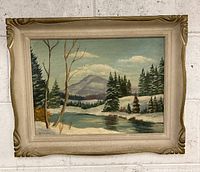Full view of framed vintage oil painting depicting a winter landscape with river, trees, and mountains.
