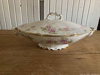 Side view of vintage Limoges covered serving dish showing floral pattern, gold trim, and one handle.