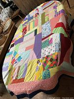 Full view of vintage patchwork quilt laid out on table showing all color patches and overall size.