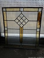 Front view of vintage stained glass window panel showing central diamond pattern and amber accent vertical strips.