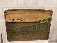 Front view of vintage Canada Dry wooden crate showing faded green logo and text "CANADA DRY" and "The Champion of Ginger Ales"