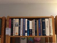 Books arranged on a wooden shelf showing political and historical titles such as Kissinger's works, The 9/11 Commission report, and Joe Klein's The Natural.