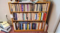 Three wooden shelves filled with books of various sizes and colors, containing titles related to psychology, psychotherapy, and fiction.