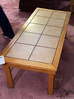 Top-down perspective of coffee table showing tile top with beige tiles in grid pattern and wooden frame