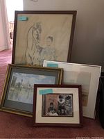 Four framed art prints arranged on the floor showing the variety in art styles and frame types.