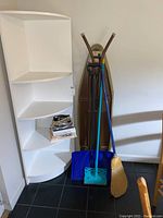 View of ironing board, broom, shovel, mop, health books, and shelving corner