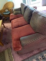 Front view of Norwalk sleeper sofa showing patterned back cushions, reddish replacement seat cushions, and one throw pillow.