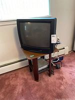Full view of Zenith 19-inch CRT TV on wood table placed near wall and baseboard heater, showing table shape and TV size.